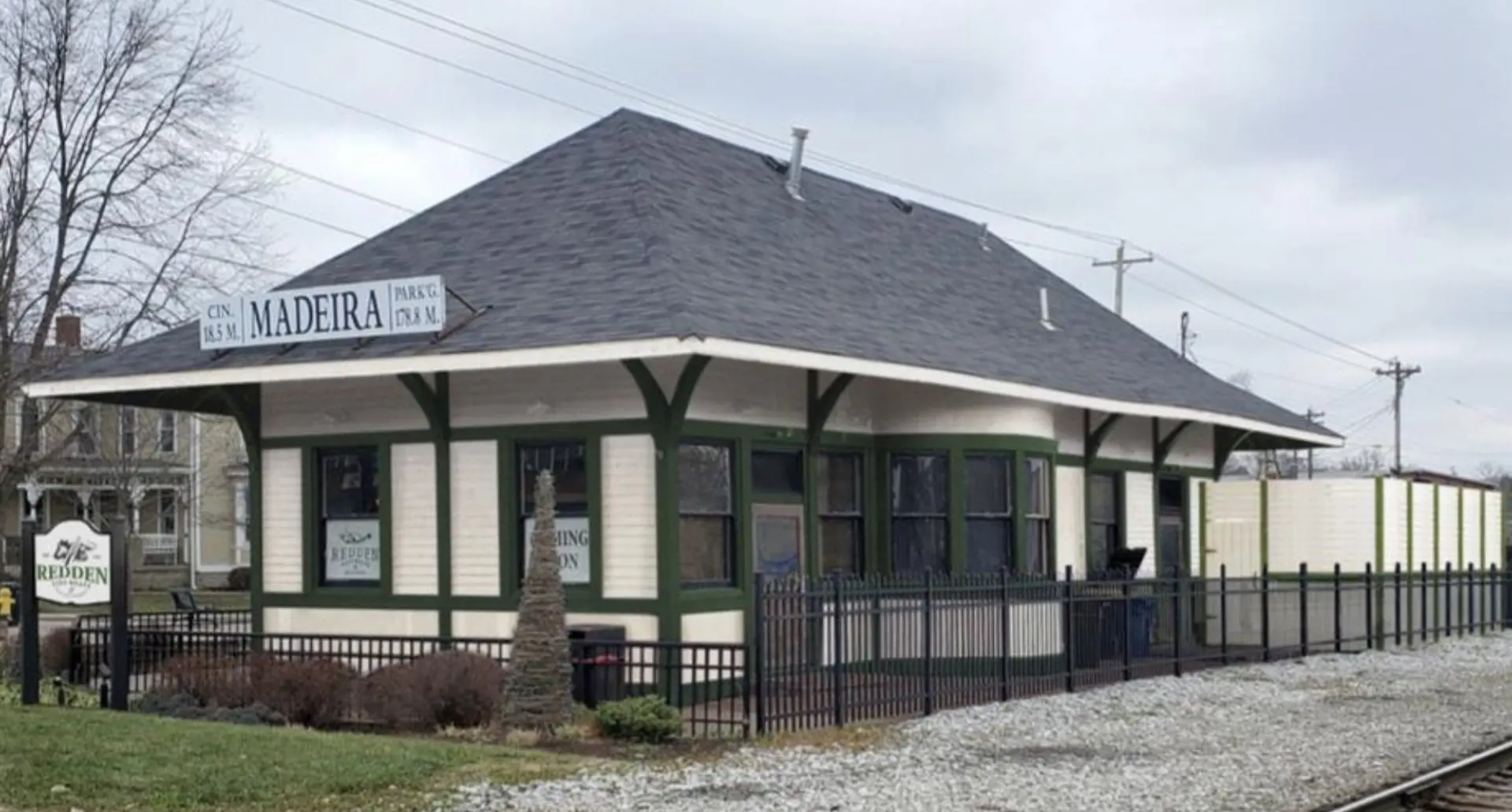 The historic Madeira train depot that houses the shop: a cream-and-green clapboard station with a wide shingled roof and a MADEIRA sign, beside the rail line