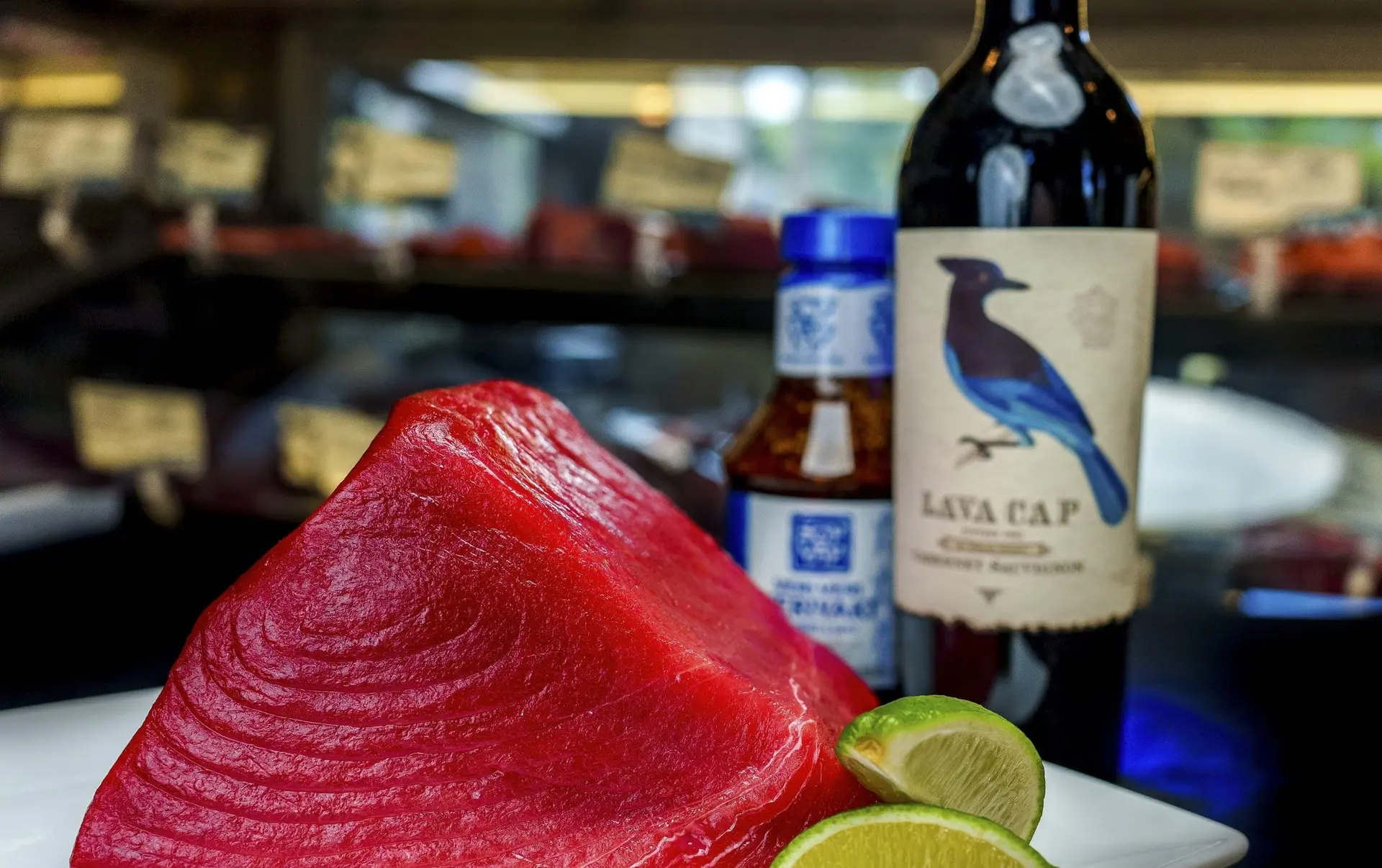 A deep-red block of raw tuna loin with lime wedges on a white plate