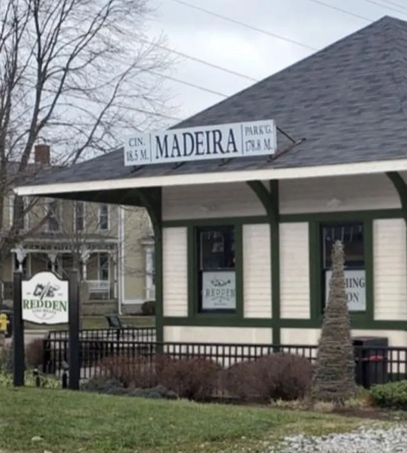 The historic Madeira train depot that houses the shop: a cream-and-green clapboard station with a wide shingled roof and a MADEIRA sign, beside the rail line